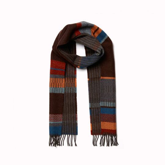 The Strathay Cinder Lambswool scarf by Wallace and Sewell is a 100% Merino Lambswool scarf displaying a deep peat palette and berry red tones to add warmth, while the burst of orange adds a lively touch.