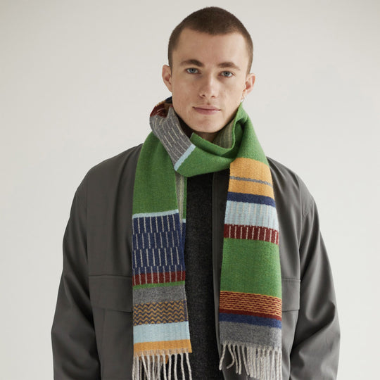 As Worn - The Strathay Pea Lambswool scarf by Wallace and Sewell is a 100% Merino Lambswool scarf in a colourful pattern of pea greens, yellows and pale blues and greys. It is a testament to the intricate craft of textile design.