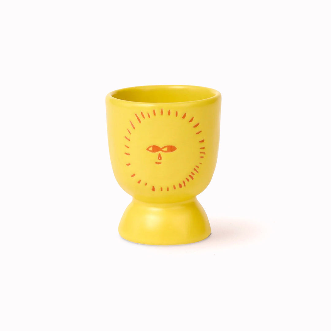 Donna Wilson stoneware egg cup in sunshine yellow featuring a sunny face. 