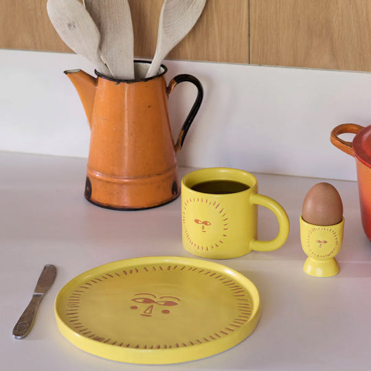 Donna Wilson stoneware egg cup in sunshine yellow featuring a sunny face. How do you like your eggs in the morning? The perfect happy egg cup for your dippy eggs and soldiers.