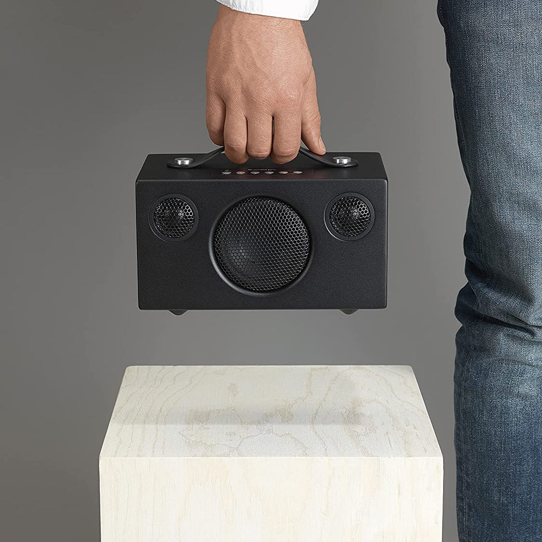 Photograph of the Audio Pro T3+ in black finish with person lifting it