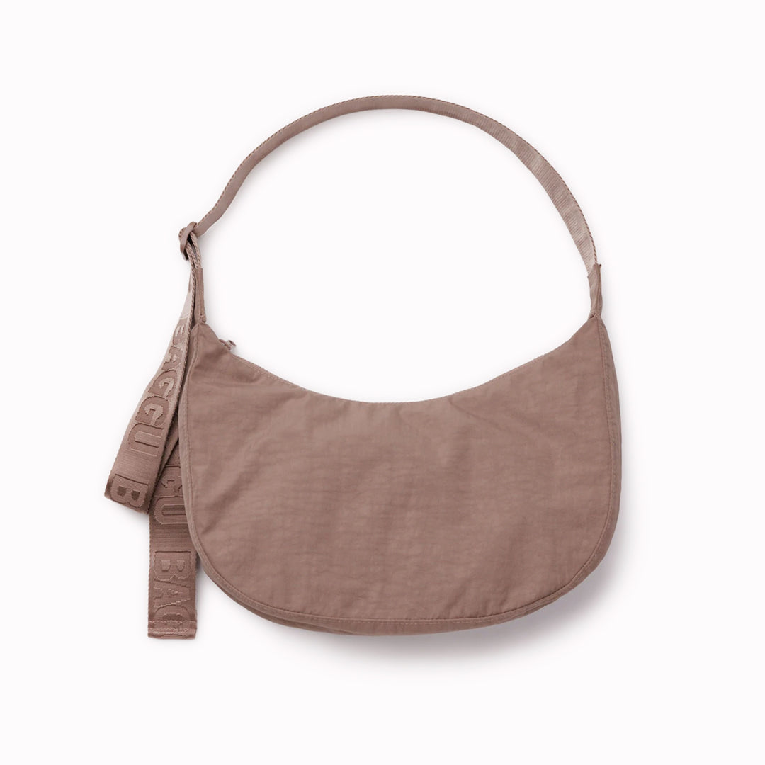 The Medium Crescent Bag in Toasted Almond from Baggu is a stylish and versatile accessory that can complement any outfit. It is made of durable nylon and features a zippered main compartment
