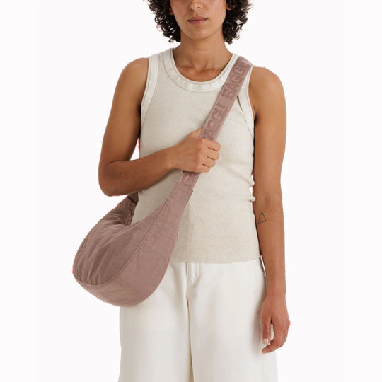 The Medium Crescent Bag in Toasted Almond from Baggu is a stylish and versatile accessory that can complement any outfit. It is made of durable nylon and features a zippered main compartment