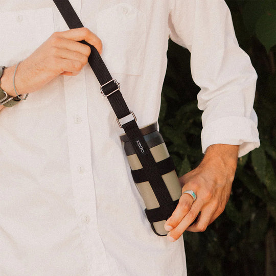 as worn by model, black travel tumbler strap with tumbler. 