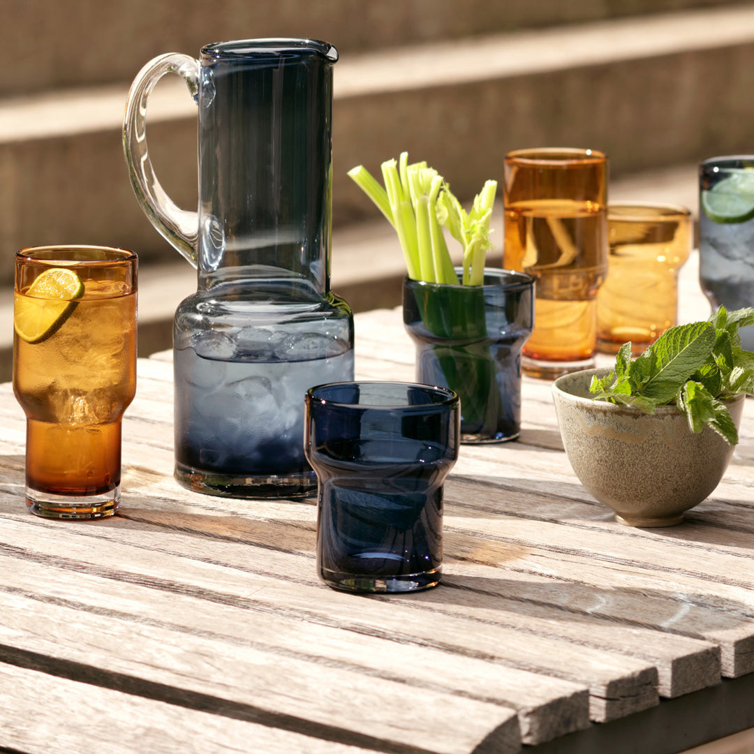 Utility Tumbler and jugs, A modern, step shaped mouth-blown tumbler made from amber coloured glass. Durable and versatile, this tumbler can be used for a variety of drinks including water, beer and short cocktails.