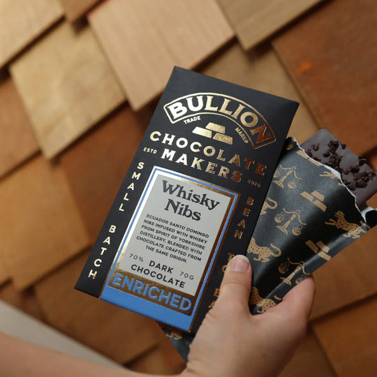 The Whisky Nib Bar from Bullion contains Ecuadorean Santo Domingo nibs infused with whisky from Spirit of Yorkshire Distillery, blended with chocolate crafted from the same origin. Shown in Hand.
