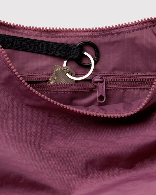 Made from recycled heavyweight nylon with a ripstop lining, it holds its form while staying lightweight. The strap adjusts to wear crossbody or over the shoulder, shifting the silhouette depending on how it’s carried.