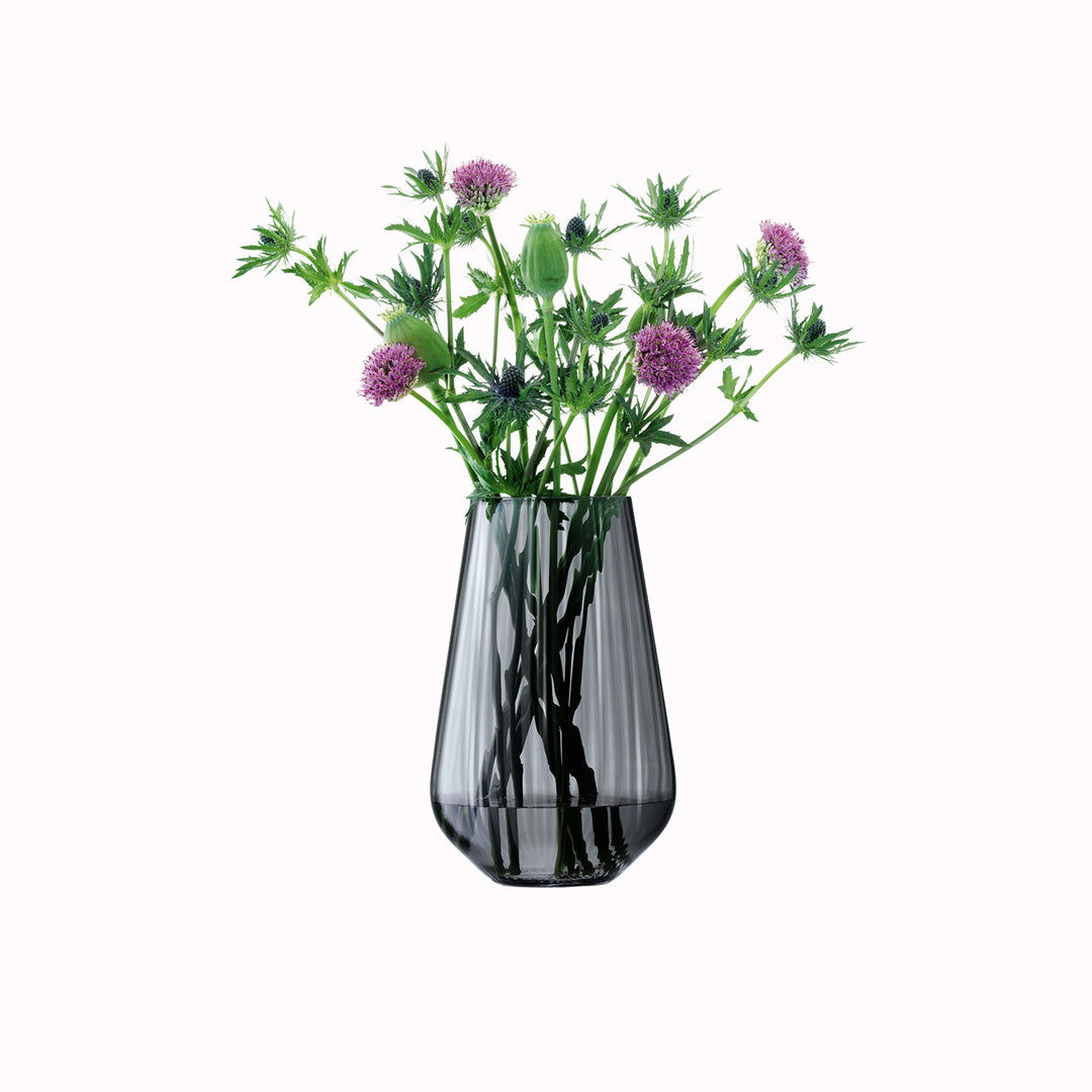 The Zinc Vase is a teardrop shaped vase made from mouth blown glass and has a pleated texture with a hand painted lustre finish. The pleated texture enhances the grey colouration that is inspired by the colour of zinc.. pictured with flowers