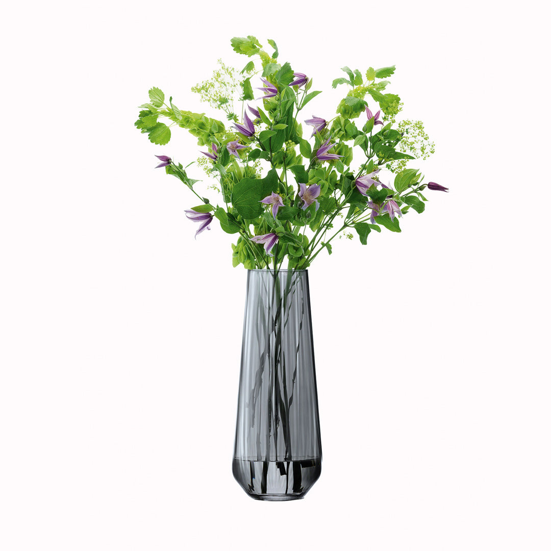The Zinc Vase is a tall teardrop shaped vase made from mouth blown glass and has a pleated texture with a hand painted lustre finish. The pleated texture enhances the grey colouration that is inspired by the colour of zinc. pictured with flowers