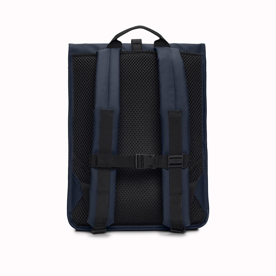 Rear View of Navy Rolltop Rucksack. Made from Rains’ signature waterproof fabric, this functional backpack has a roll-top closure with an adjustable strap featuring a loop for a bike lock or similar. It has a large main compartment, and an easy-access front pocket and side-access laptop compartment both with a water-repellent zipper closure.