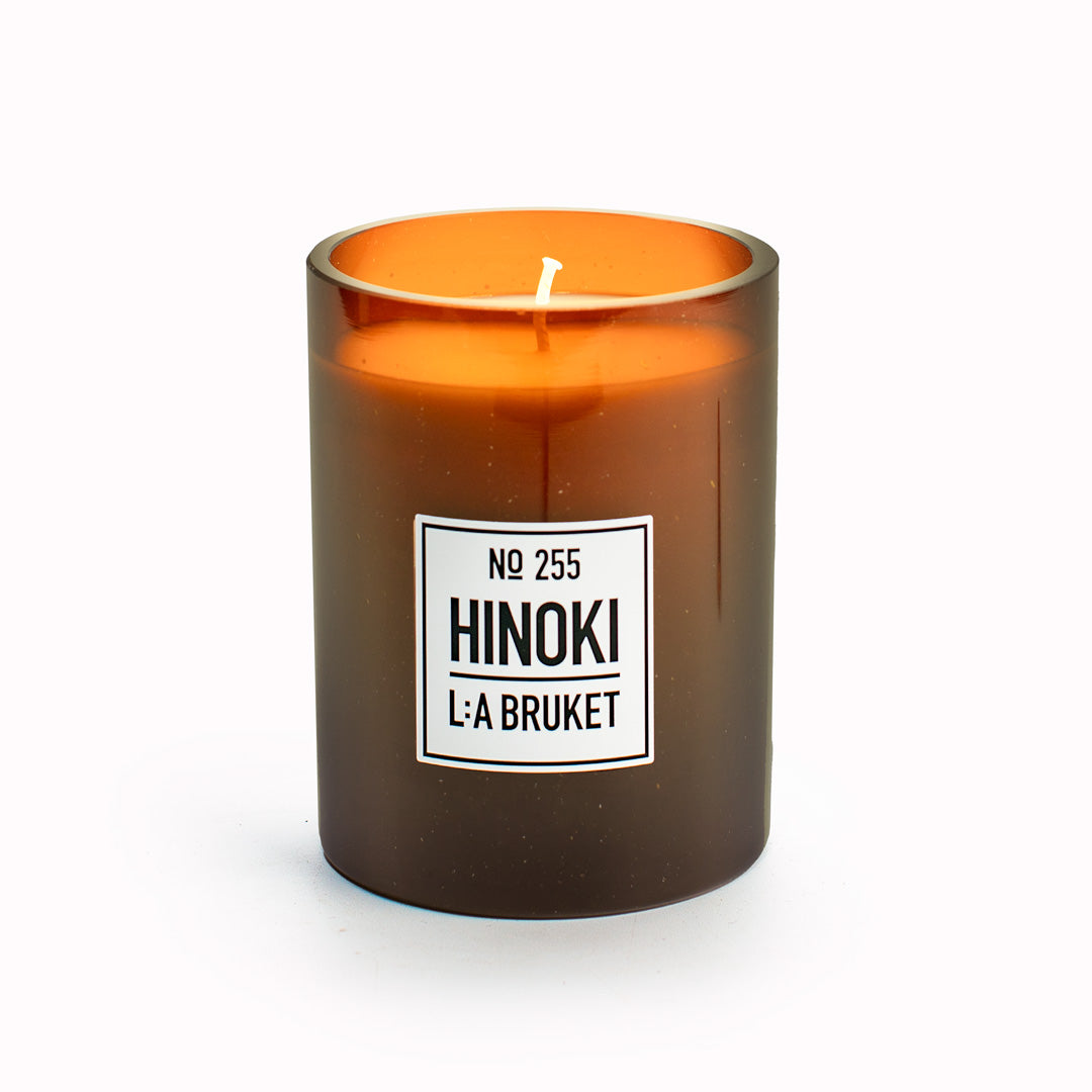 Hinoki Large Refillable Scented Candle from L:A Bruket with lid off. Made of wax from organic soy with a burn time of more than 45 hours.  The Hinoki scent is a woody outdoor fragrance of Japanese cypress, cedarwood and nutmeg. A beautifully fragranced soy candle, Swedish home fragrance at its best.
