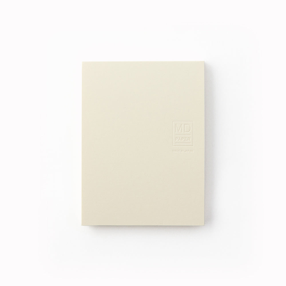Showing cover. A7 memo pad with embossed off-white cover and plain sheets. Designed to work alongside the MD Paper notebook series, it uses the same quality paper and same plain layout so you can seamlessly add notes into pages in your MD Paper Plain notebook. It is sticky on one side, but you can write on both sides. 80 tear off pages.