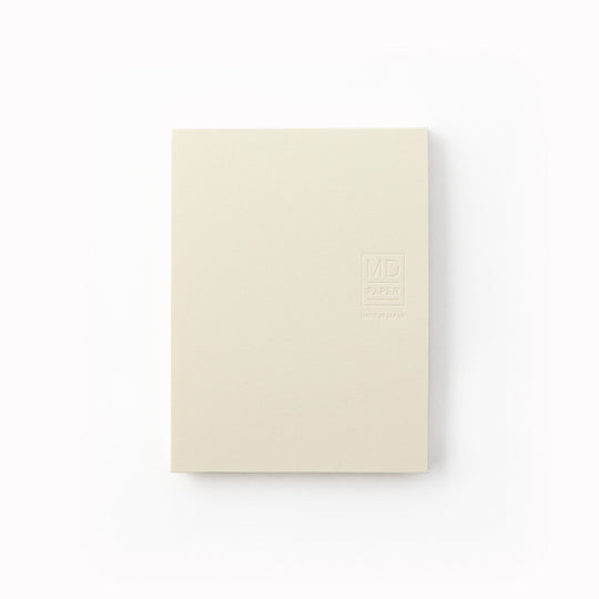 Showing cover. A7 memo pad with embossed off-white cover and plain sheets. Designed to work alongside the MD Paper notebook series, it uses the same quality paper and same plain layout so you can seamlessly add notes into pages in your MD Paper Plain notebook. It is sticky on one side, but you can write on both sides. 80 tear off pages.
