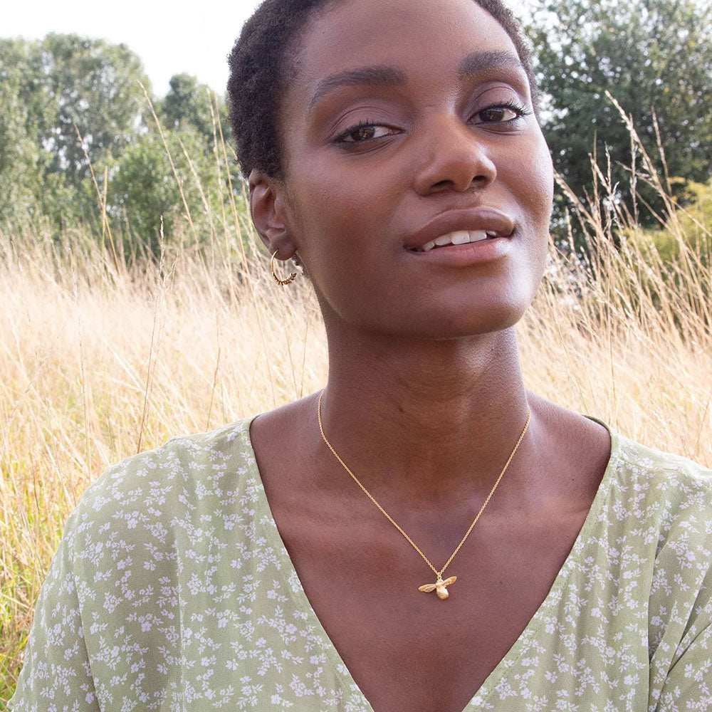 Model wearing nicely detailed gold Baby Bee necklace from Alex Monroe's Classics jewellery collection.