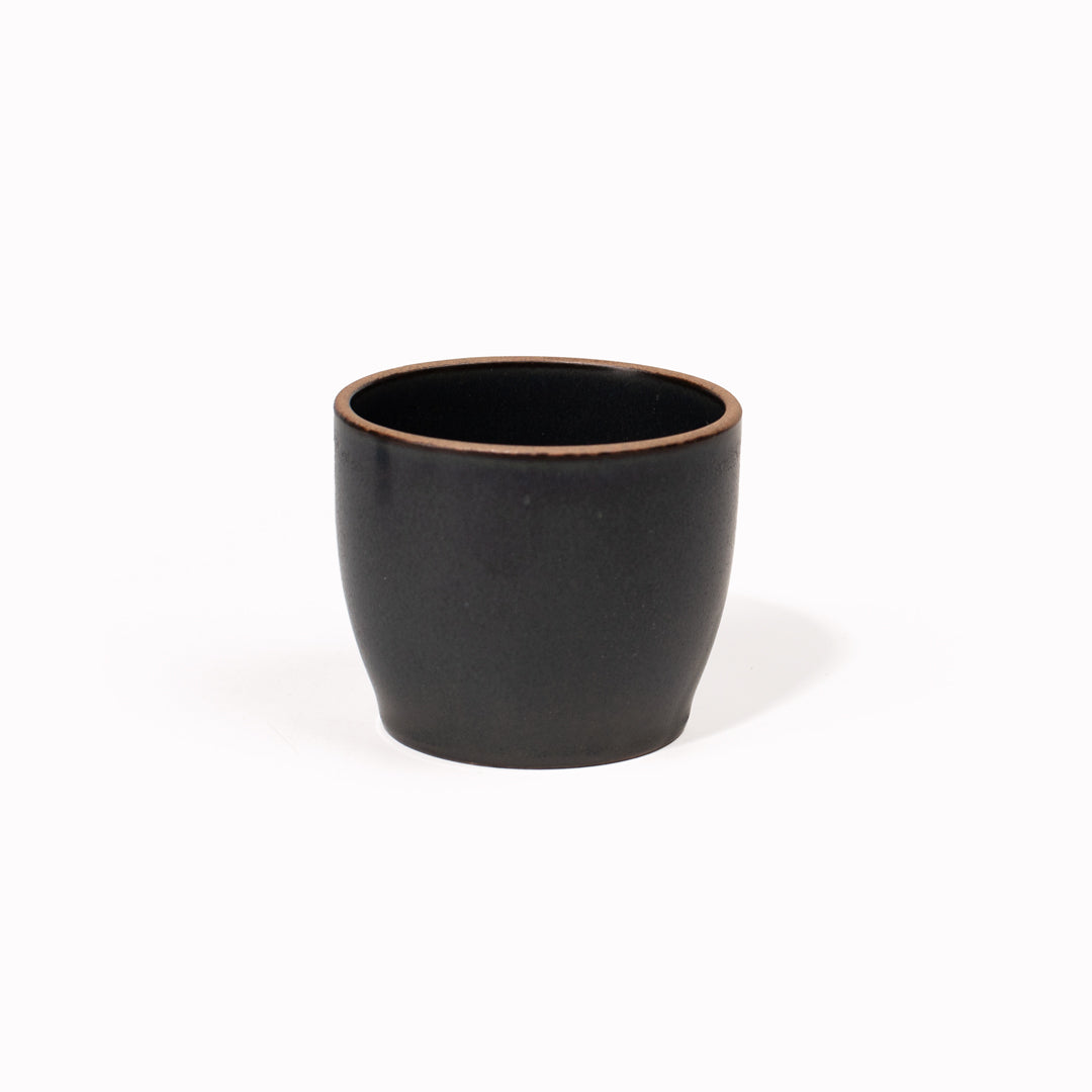 The Black Nori Porcelain Tumbler is a Japanese manufactured small tea, coffee, or juice cup from Kinto. The porcelain has a tactile sloping side and smooth finish which feels pleasing in your hands. The glaze is a tasteful matt black stone with raw porcelain edges in the Japanese style. 