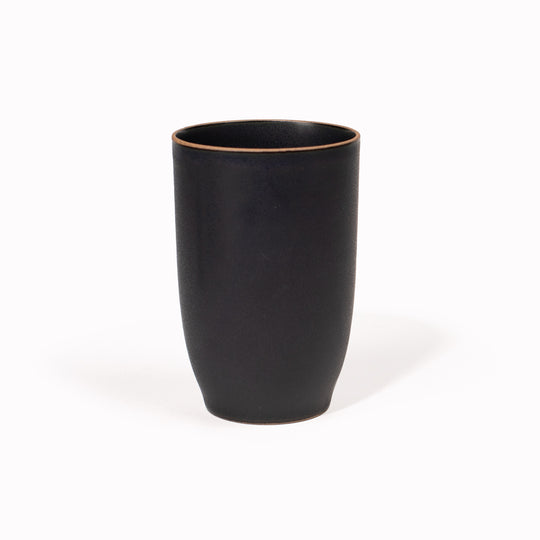 The 350ml Black Nori Porcelain Tumbler  is a Japanese manufactured tall black tea, coffee or juice cup from Kinto. The porcelain has a tactile sloping side and smooth finish which feels pleasing in your hands. The glaze is a tasteful matt black stone with raw porcelain edges in the Japanese style. 