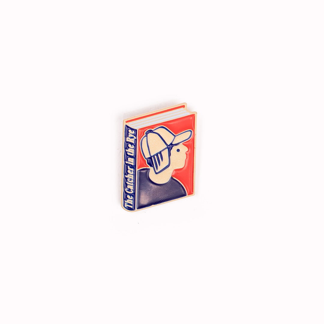 Enamel pin badge featuring an illustrative book cover interpretation of the modern American, coming of age, classic novel 'The Catcher In The Rye' by J.D. Salinger.