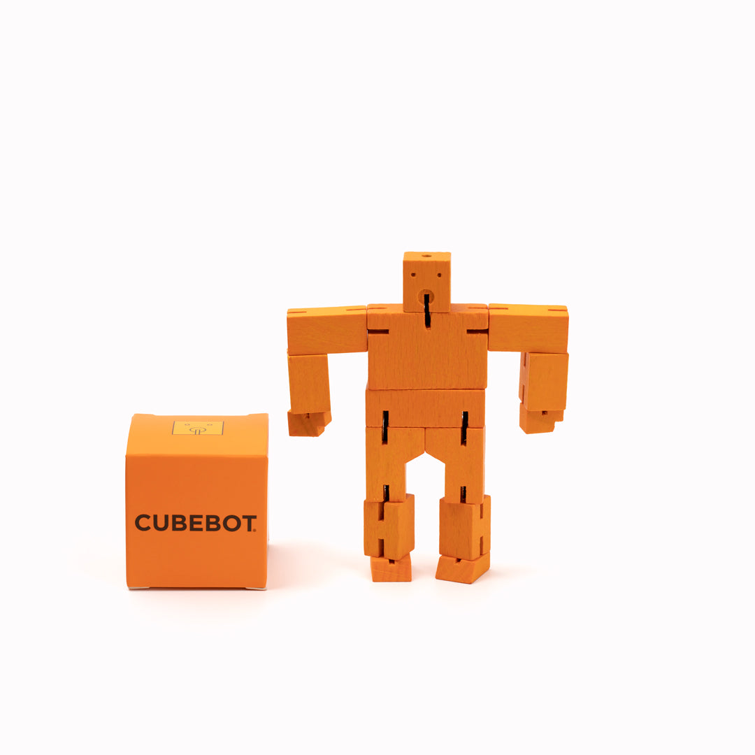 Orange Cubebot by Areaware is a fun wooden toy robot that folds out of a perfect cube shape. Part puzzle, part posable toy they are inspired by Japanese Shinto Kumi-ki puzzles and can be positioned to hold dozens of poses.   Made from Beech and elastic, water based paint. Posable and decorative. 11 cm tall, 14 cm arm span