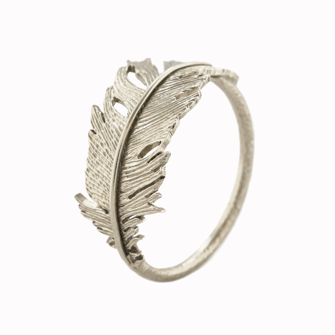 A single fallen feather curves to form a ring with a lightly textured band, from award winning London jeweller Alex Monroe.