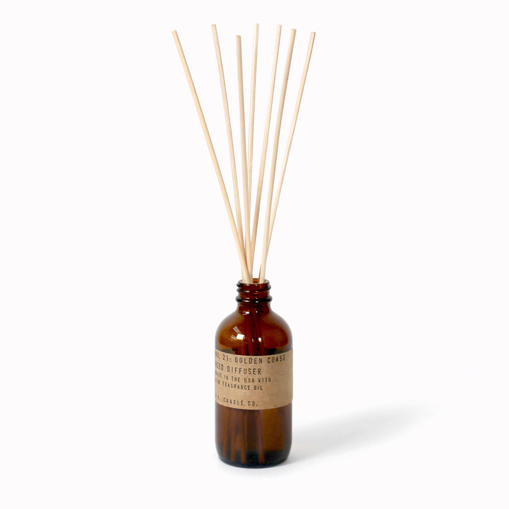 P.F. Candle Co Golden Coast Reed Diffuser in an apothecary-inspired amber glass bottle with their signature kraft label and rattan reeds. Low-maintenance scent, all day long