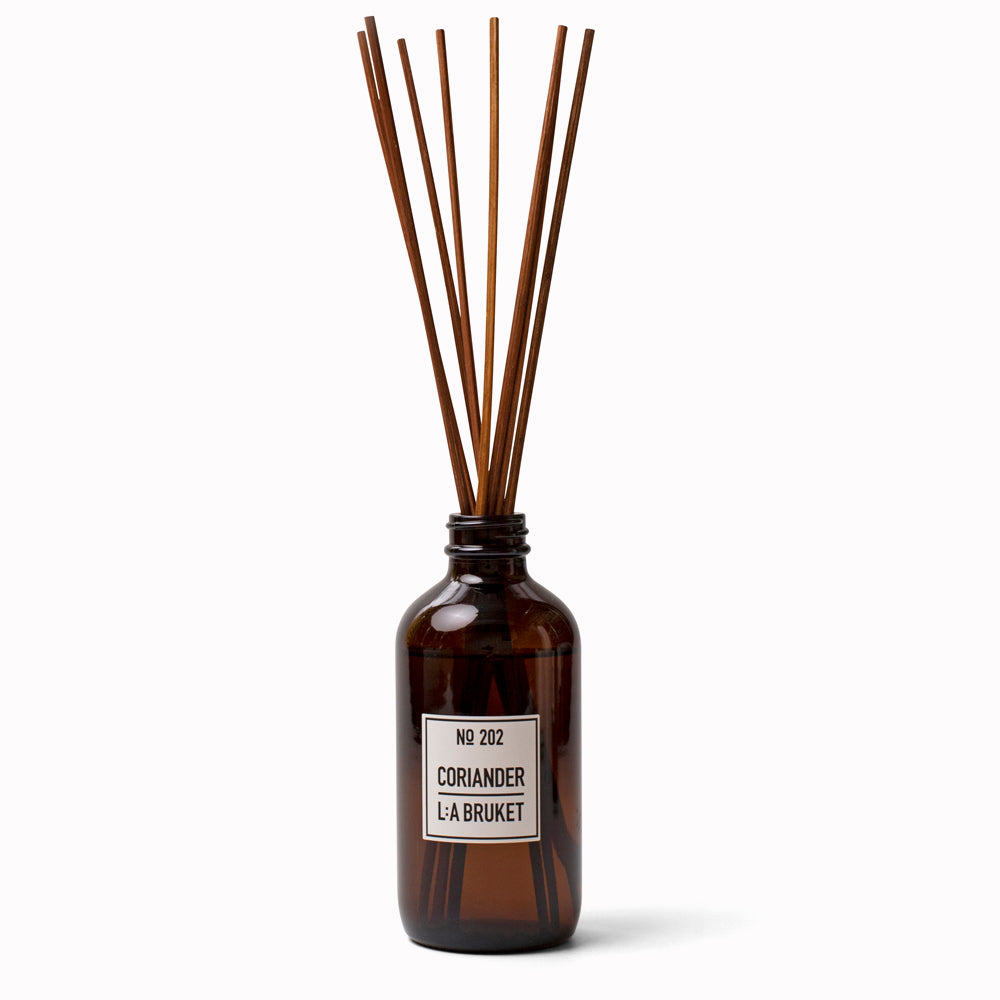 Coriander Reed Diffuser 202 from L:A Bruket. Room diffuser with a fresh scent of coriander and mint leaves, presented in an amber glass bottle with natural rattan reed sticks. The scent is made from a natural vegetable based solubiliser derived from renewable sources.