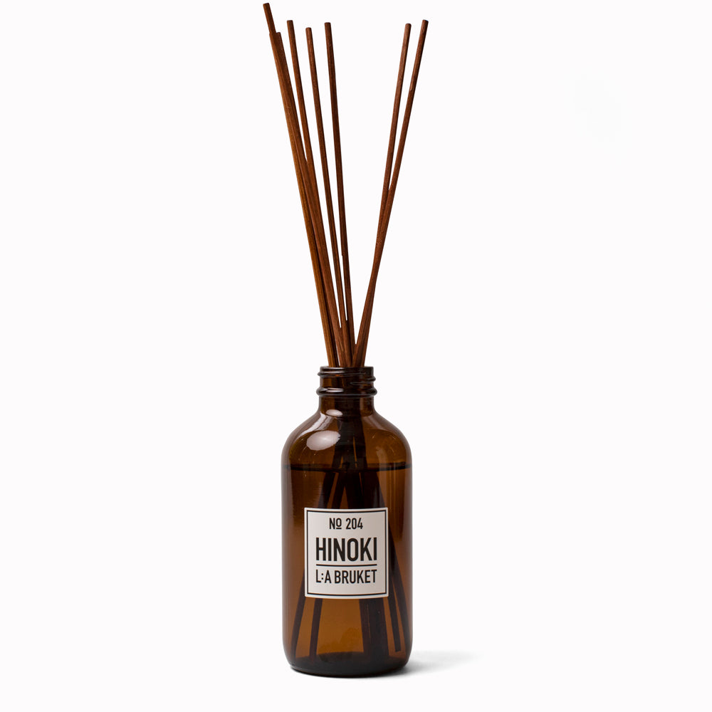 Hinoki Reed Diffuser 204 from L:A Bruket. Room diffuser with a fresh scent of Hinoki, a woody outdoor scent of Japanese cypress, cedar wood and nutmeg. It is presented in an amber glass bottle with natural rattan reed sticks with the scent made from a natural vegetable based solubiliser derived from renewable sources.
