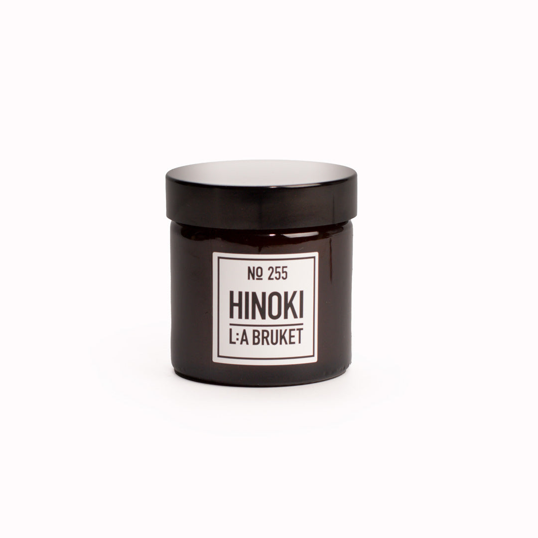 Hinoki Travel Sized Scented Candle with Lid from L:A Bruket. Hinoki scented travel candle from L:A Bruket, made of wax from organic soy with a burn time of more than 15 hours. The candle is filled by hand in a mouth-blown amber tinted glass.