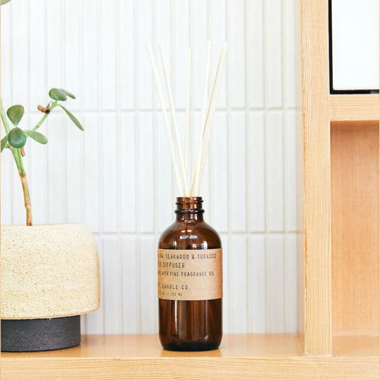 Teakwood and Tobacco Reed Diffuser from PF Candle Co in a lifestyle setting on a shelf with succulent plant
