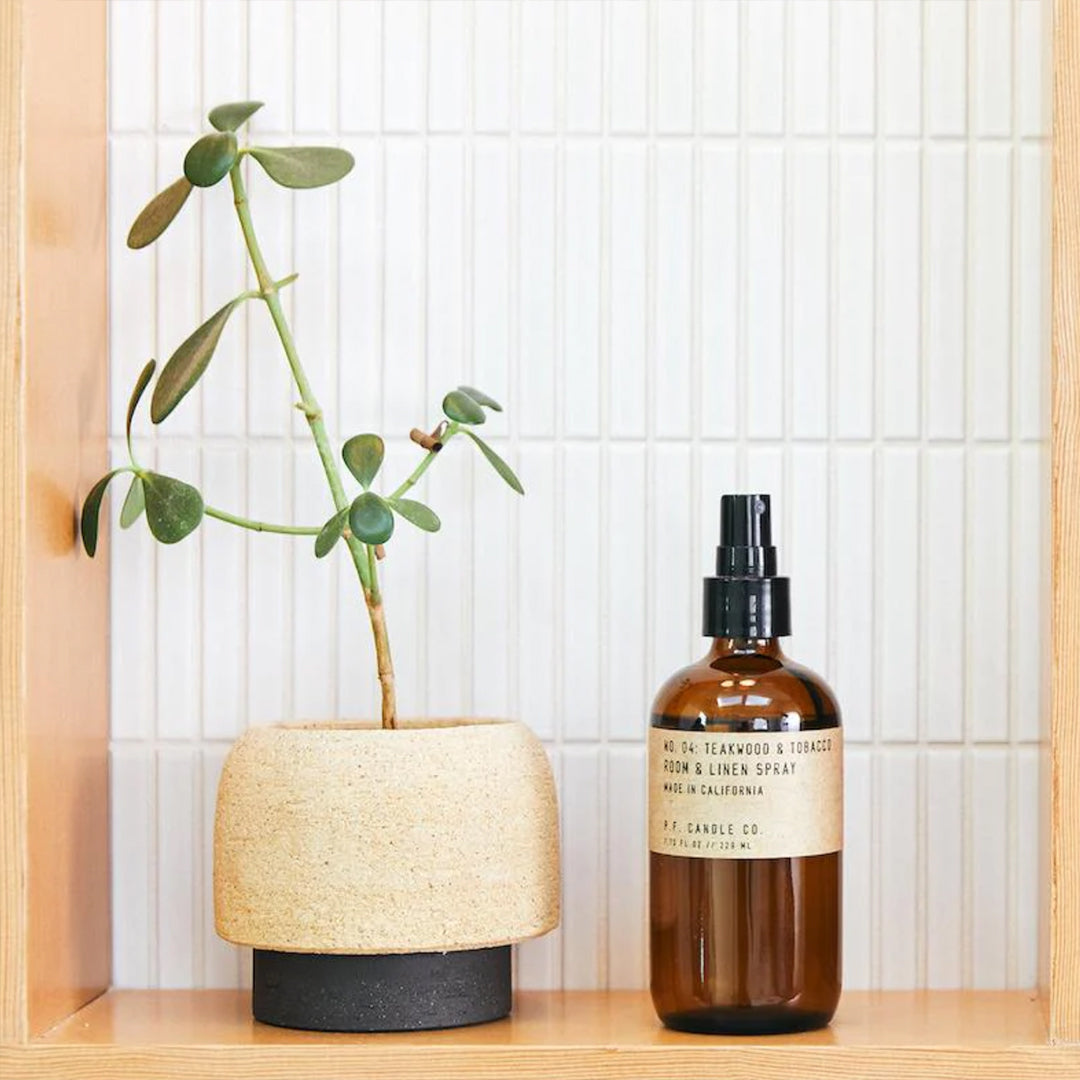 Room and Linen Spray with Teakwood and Tobacco Scent from PF Candle Co on a shelf with succulent plant