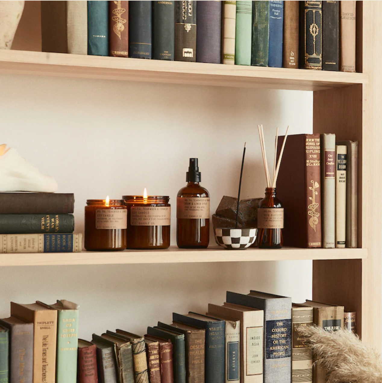 Teakwood and Tobacco Fragranced collection of candles, room sprays and reed diffusers on a book shelf