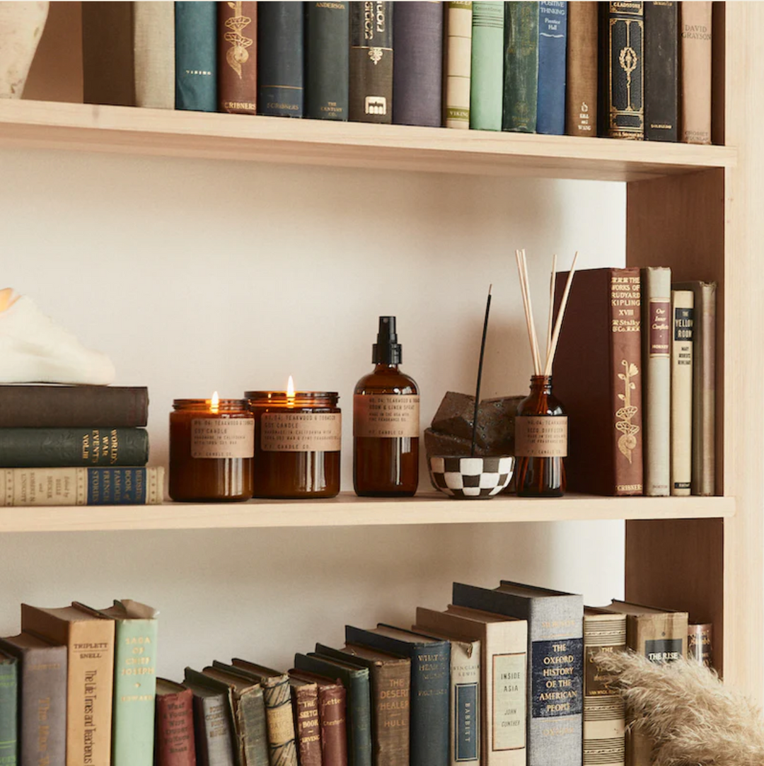 Teakwood and Tobacco Fragranced collection of candles, room sprays and reed diffusers on a book shelf