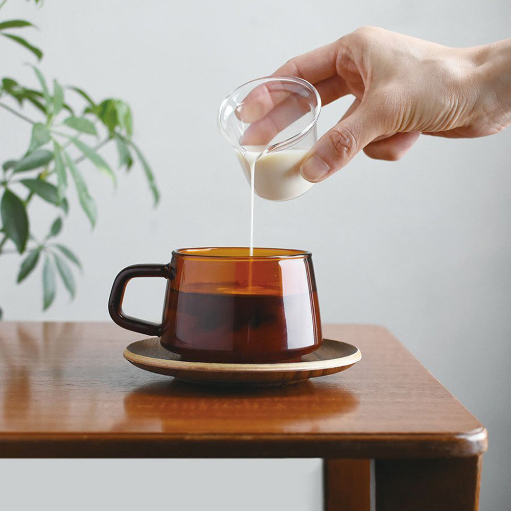 Graceful and nostalgic sepia toned glass cup with milk pourer and teak saucer from Kinto, as part of their Sepia range.