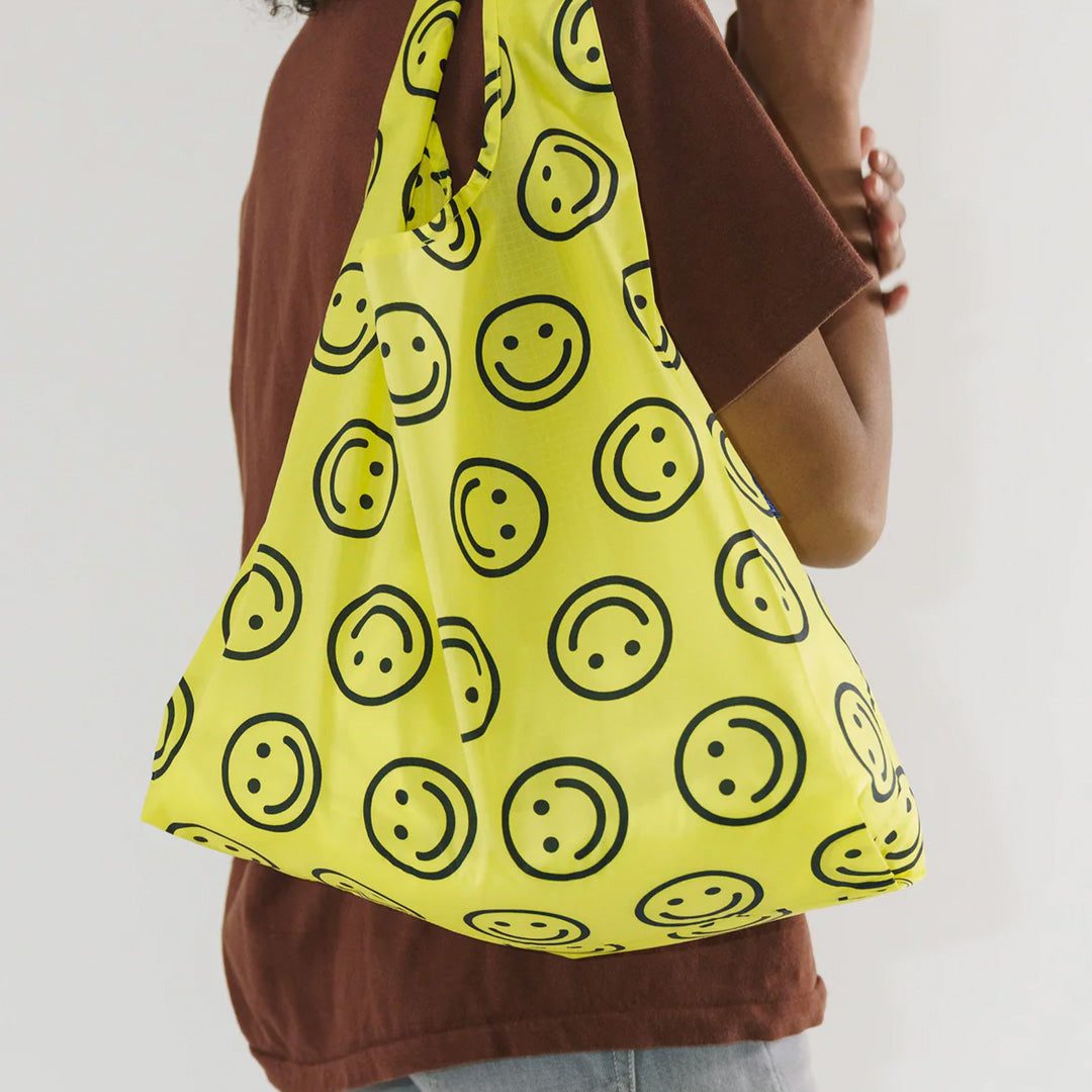 Yellow Happy Reusable shopping bag with model by Californian maker Baggu made from super strong ripstop nylon to transport pretty much anything, so long as it’s under 20kg. It tucks away into a neat little pouch made from its own handle (to minimise waste)
