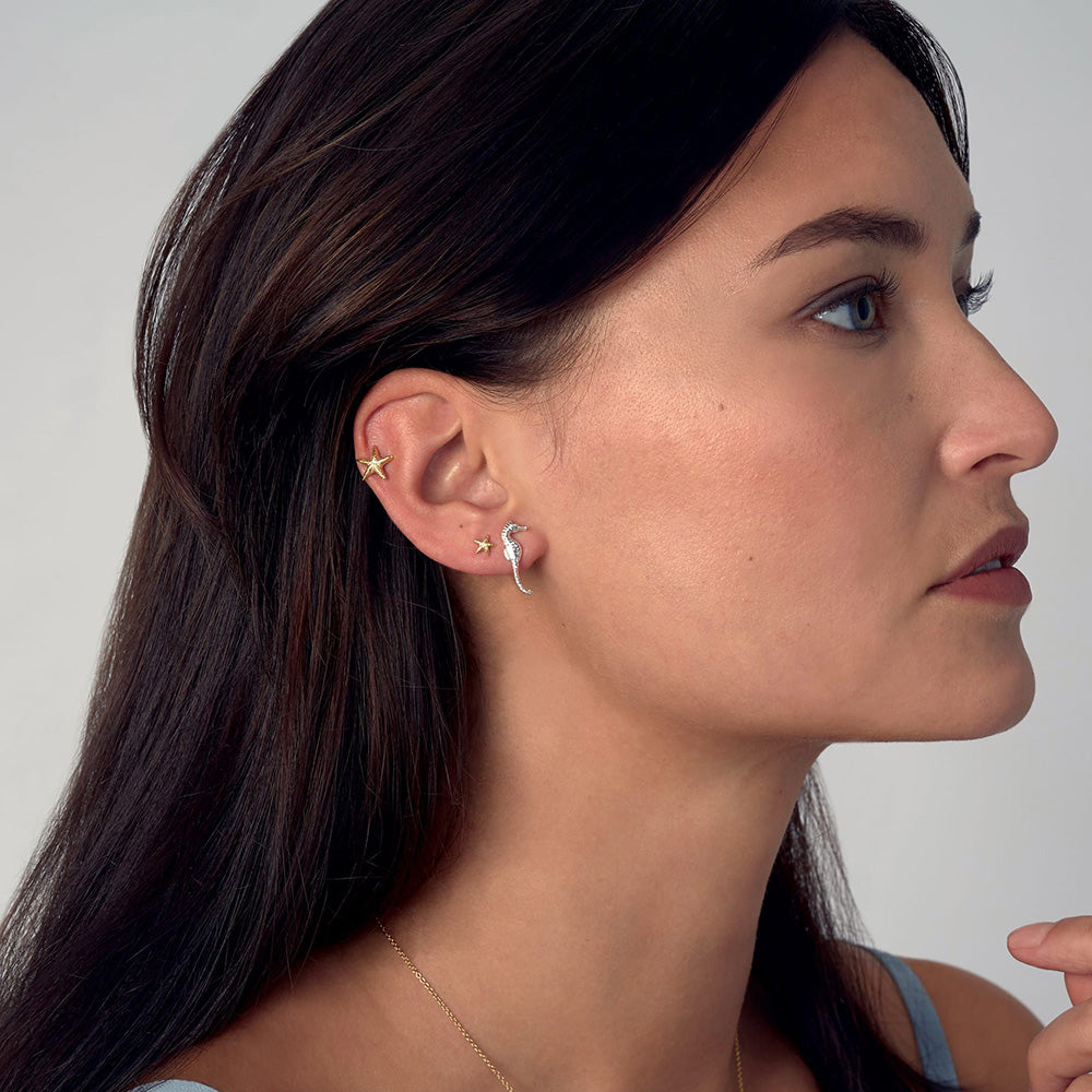 Gold Asymmetric Starfish stud earrings on model by Alex Monroe. Jewellery made in England.