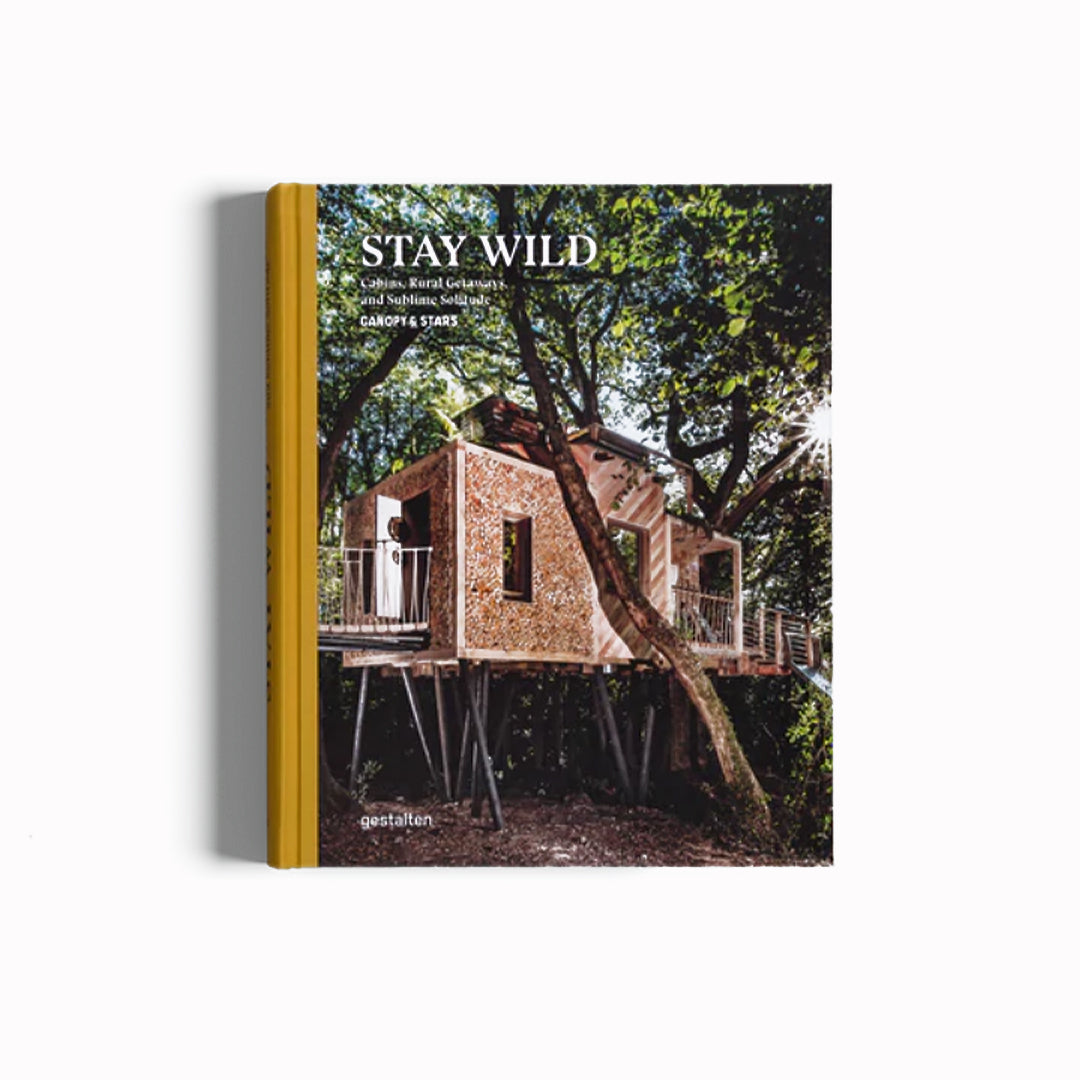 Stay Wild Travel Book, Cover. Cabin on stilts amongst trees. From towering treehouses, compact cabins, houseboats, yurts, and mobile homes that let you cook your meals al fresco whilst the campfire flickers, this book showcases alternative travel’s astounding diversity and enriching qualities.