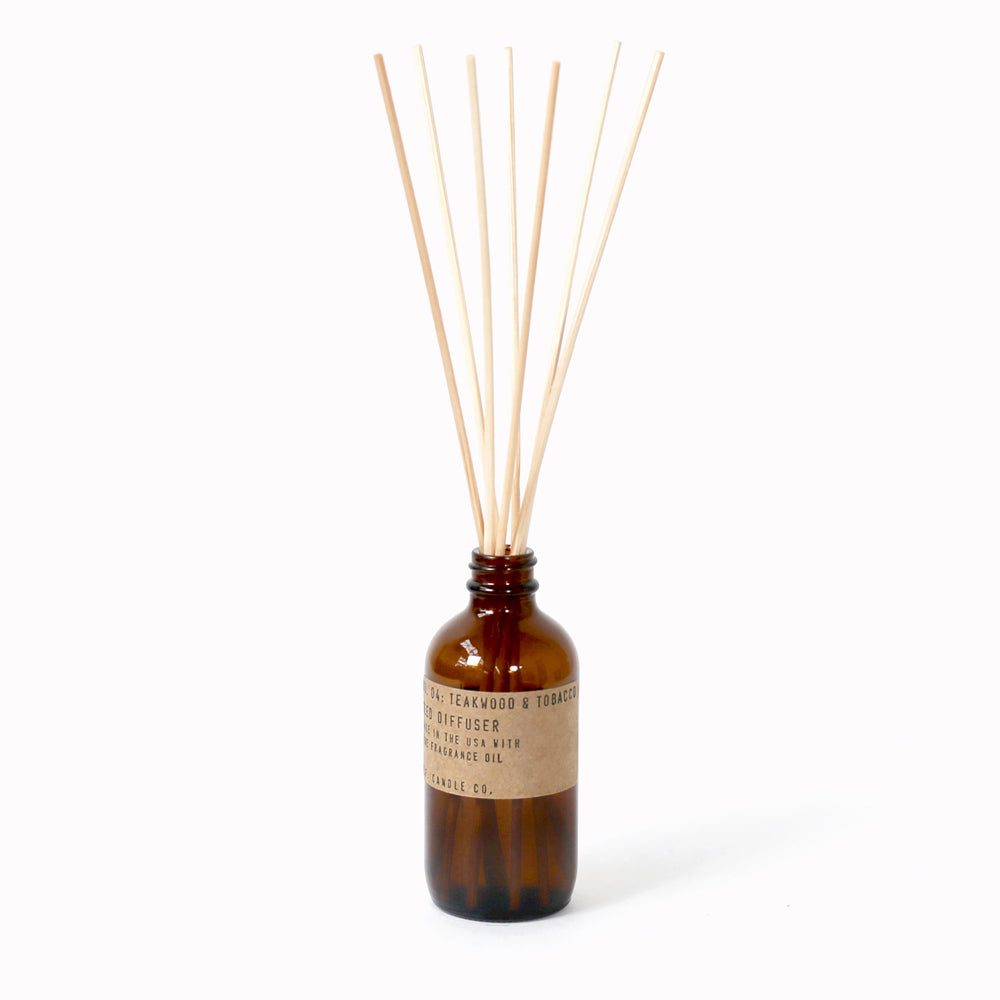 P.F. Candle Co Teakwood and Tobacco Reed Diffuser in an apothecary-inspired amber glass bottle with their signature kraft label and rattan reeds. Low-maintenance scent, all day long