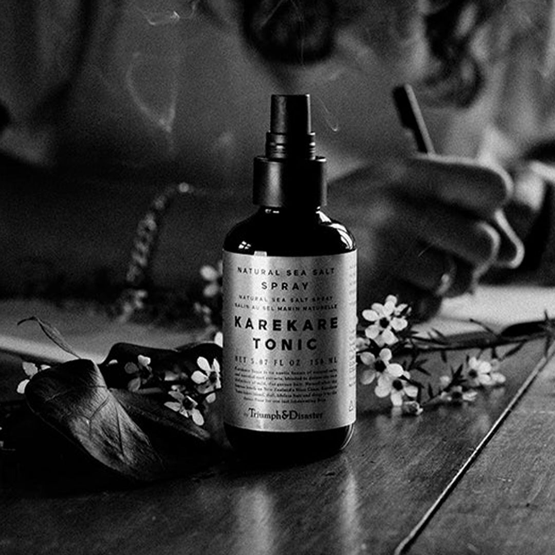 Karekare Hair Tonic is Triumph & Disaster's all natural fusion of sea salt spray and essential root extracts, blended to deliver textured beach hair miles away from the coast.  lifestyle image on table