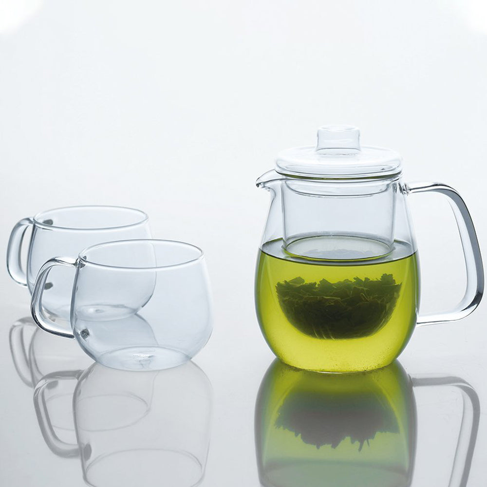This Unitea teapot with built-in glass strainer by Kinto Japan has a capacity of 720 ml, which is perfect 3 to 4 small cups or 2 large mugs of tea. Teapot with green tea and 2 cups on table..