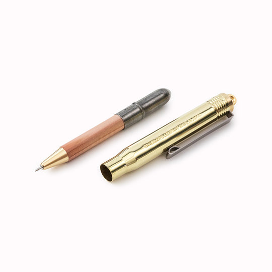 TRC ballpoint pen open on table, it has a brass lid that it fits compactly inside when not in use. When you are using the pen, simply place the lid on the end and you have a full-sized pen to write with! 