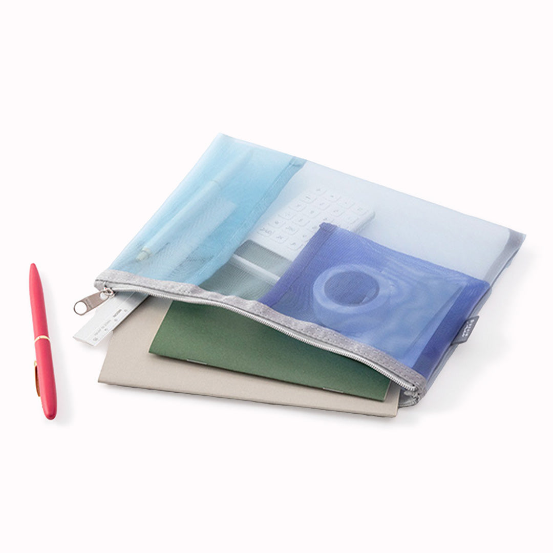 Light Blue mesh pen or tool pouch lifestyle on table full with pens and items from Midori, the Japanese Stationery brand has many uses, as a pencil case or a makeup bag.