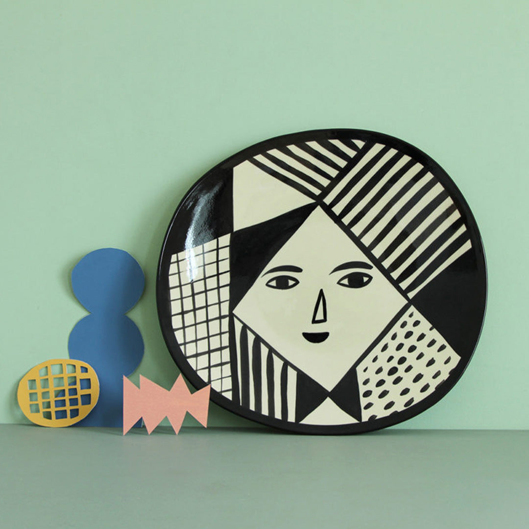 Mono Face Platter Lifestyle image from Donna Wilson, to serve up a feast. Featuring a black and white face and abstract patterns, every platter is painted by hand, meaning each one is unique.